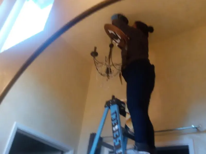 Electrician installing a chandelier in a Forestdale residence